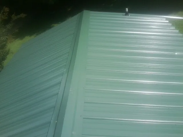 New green metal panels meeting at the ridge of a roof — Flat Roof Repair work by our crew in Oakham