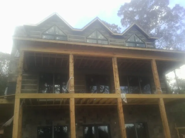 Dormers and porch framing on a large log home under construction — Roof Coating work by our crew in Oakham