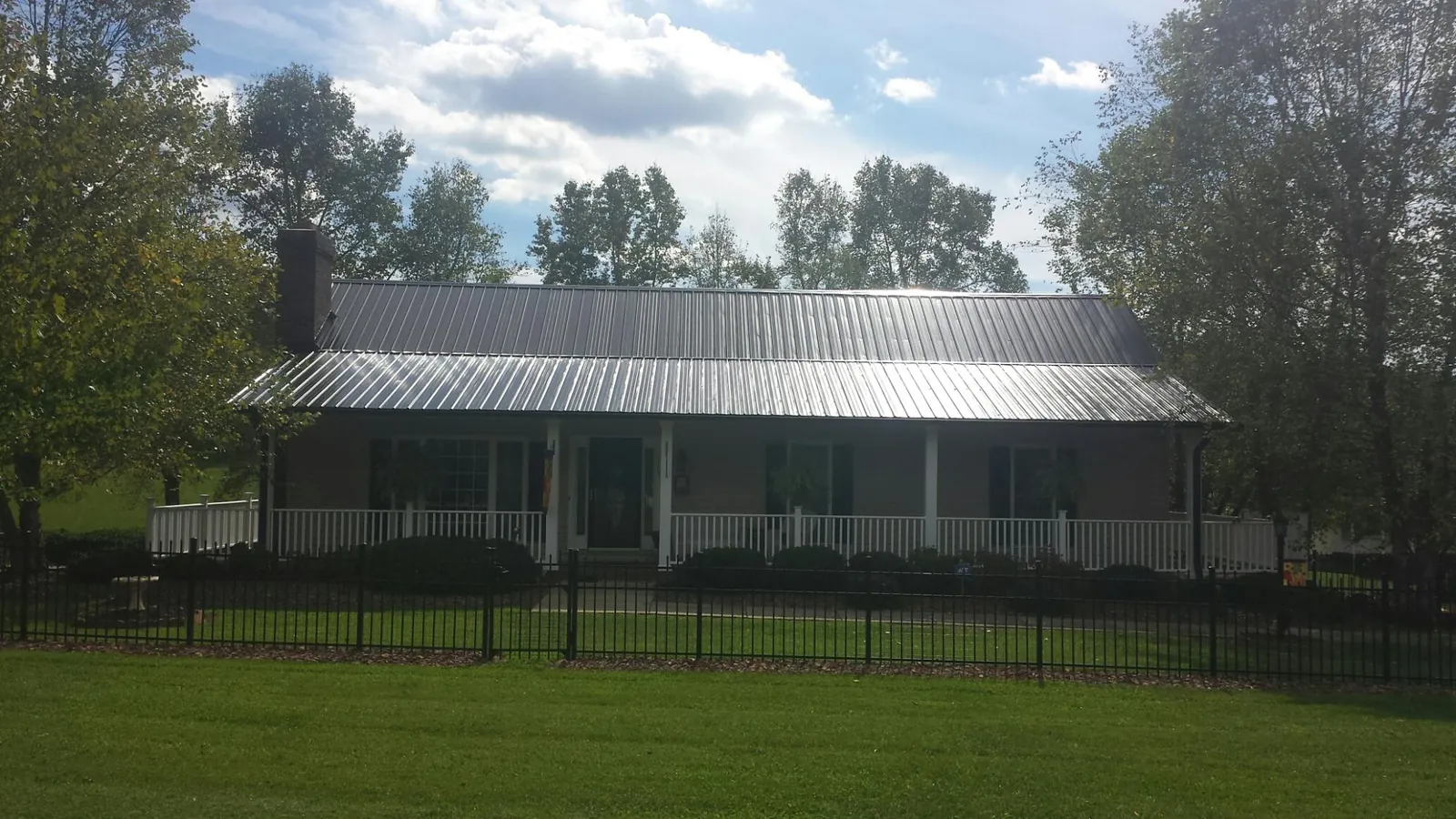 Gray metal roof on a brick ranch with a full width front porch — Gutter Guard Installation work by our crew in Oakham